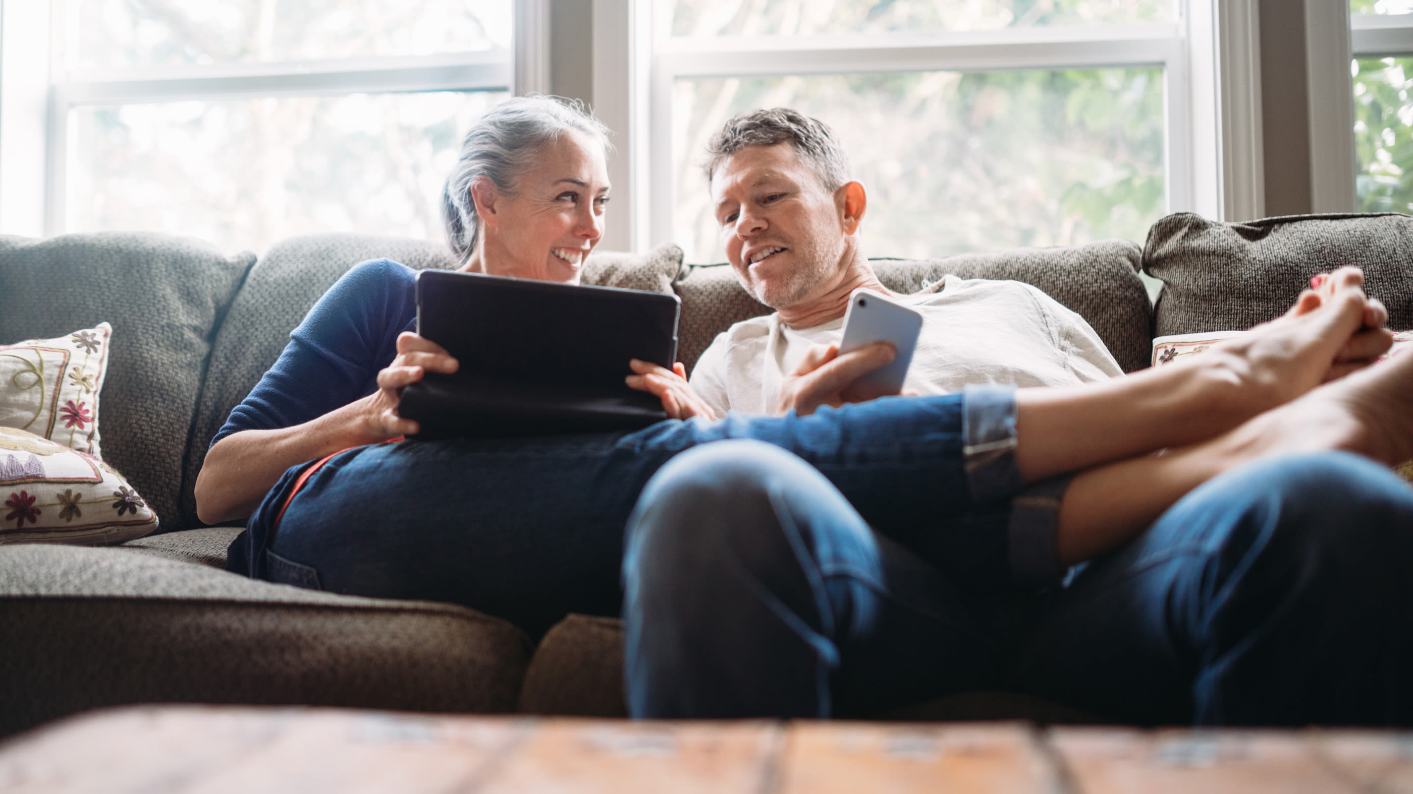 Frau und Mann sitzen auf Sofa und schauen auf ein Tablet-Computer.