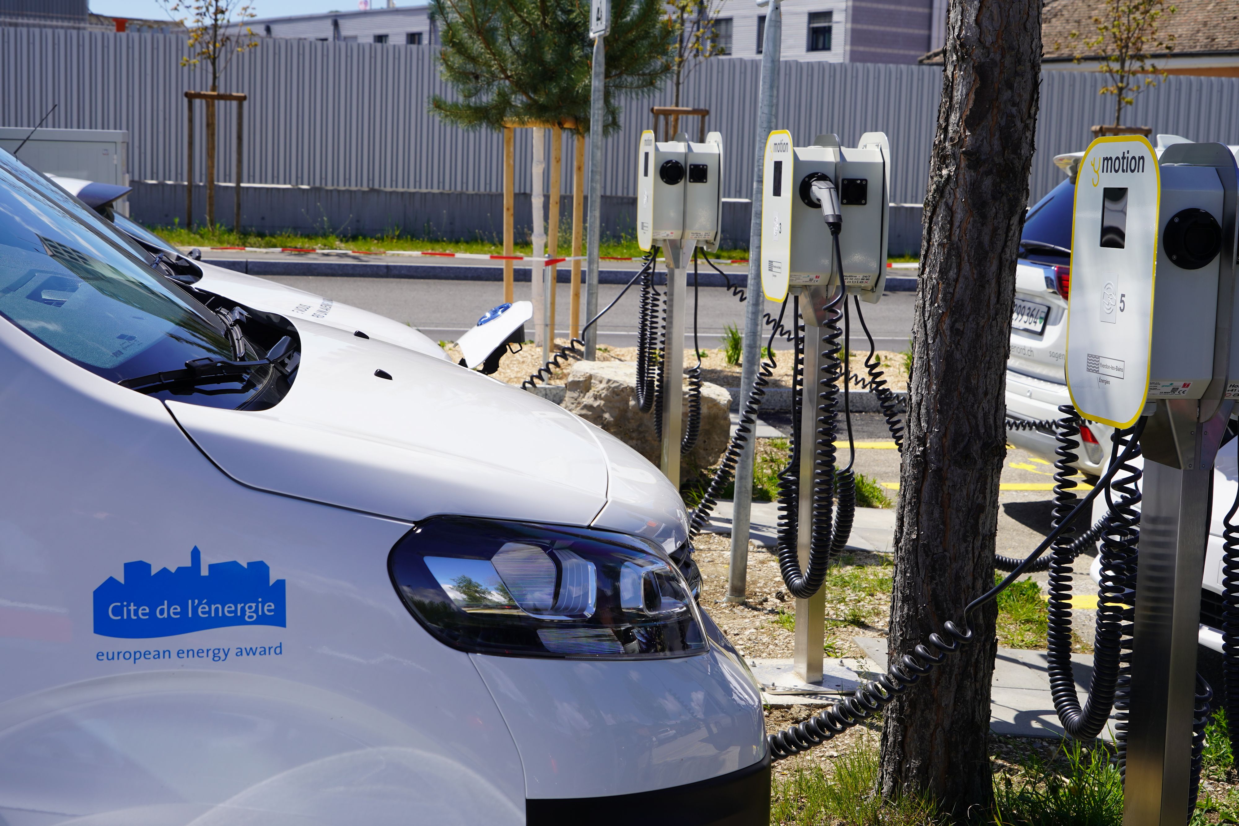 Furgone elettrico con il logo del marchio «Città dell'energia» in carica presso una stazione di ricarica esterna