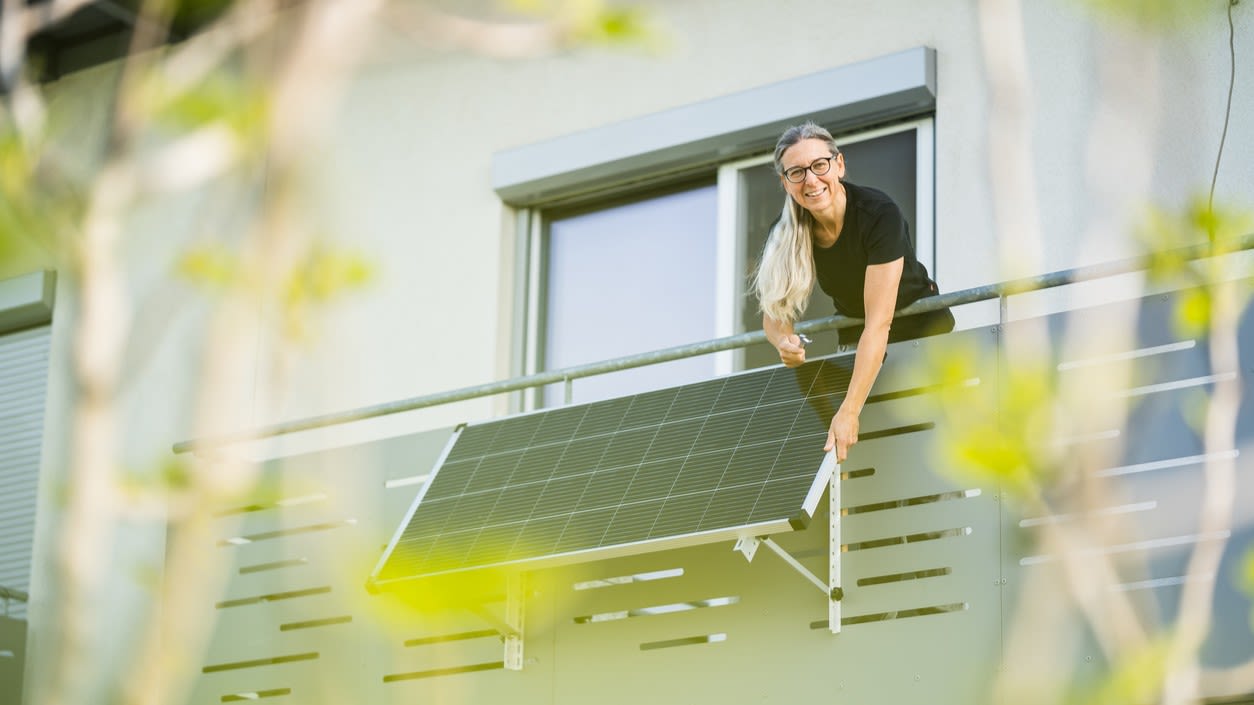 Une dame fixe une centrale électrique de balcon à la balustrade de son balcon.