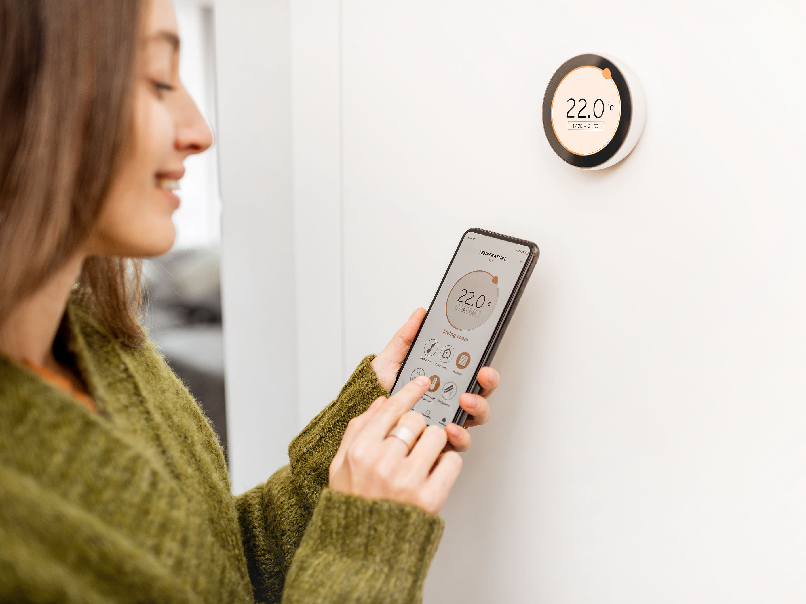 Una donna controlla il calore nella sua casa con il suo telefono cellulare.