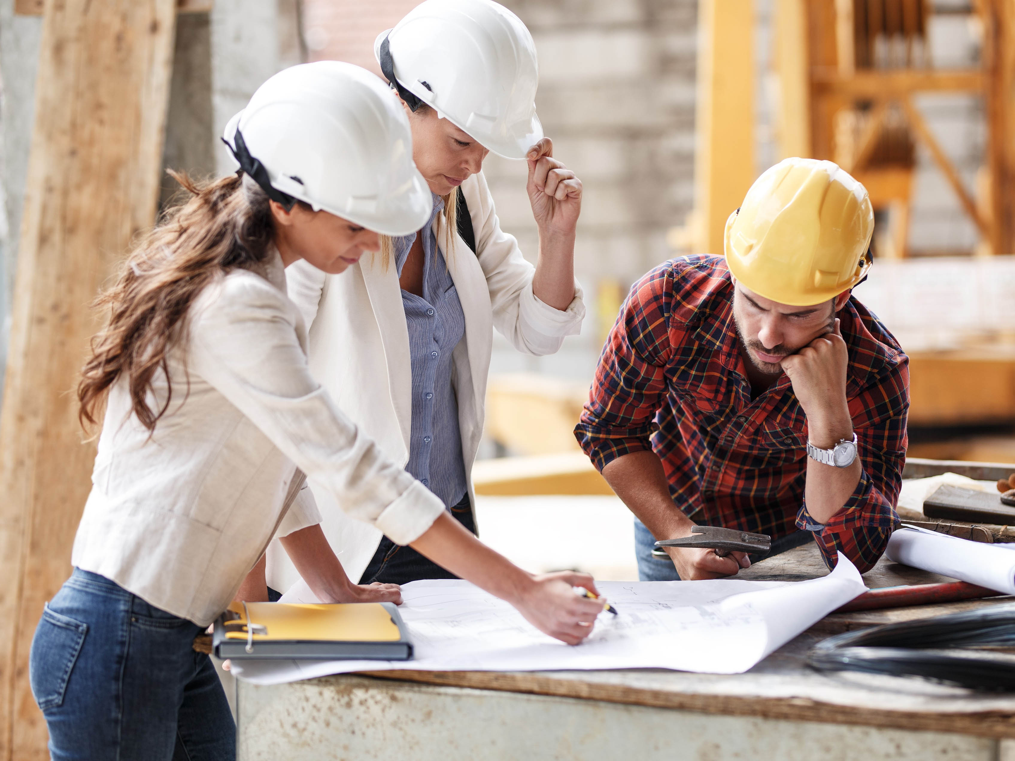 3 personnes regardent des plans sur un chantier