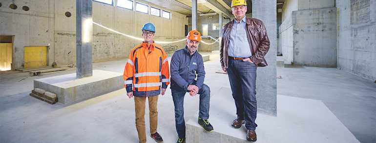 Reto Mathys, Salvatore Tomai und Fritz Schmid stehen in der noch leeren Wärmezentrale im neuen Schulhaus