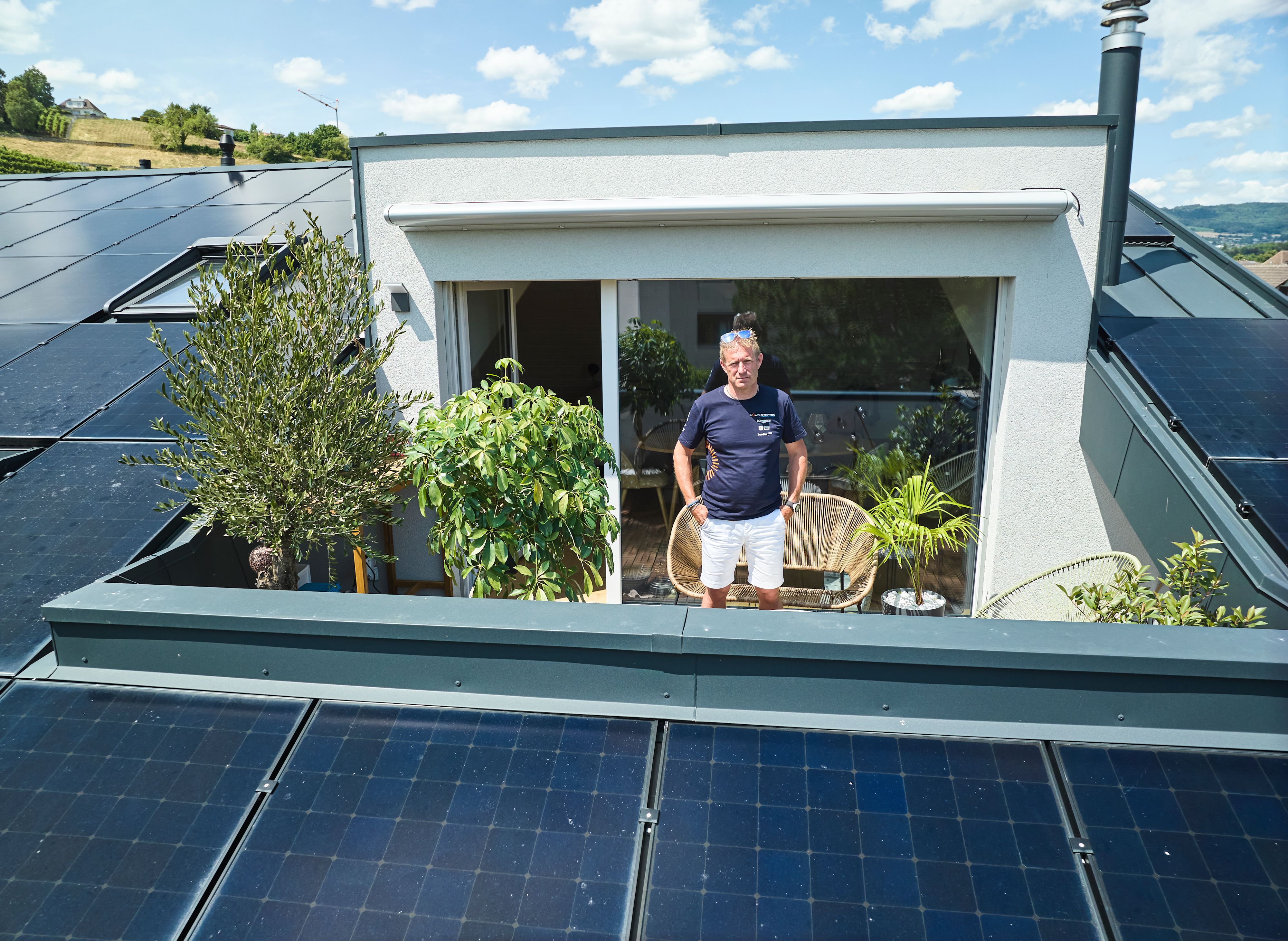 Raphaël Domjan se tient sur le balcon de sa maison entouré de panneaux photovoltaïques.