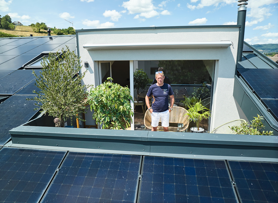 Raphaël Domjan steht auf dem Balkon seines Hauses umgeben von Photovoltaikmodulen.