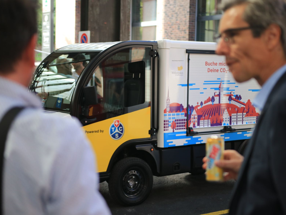 Deux hommes discutent devant une camionnette électrique.