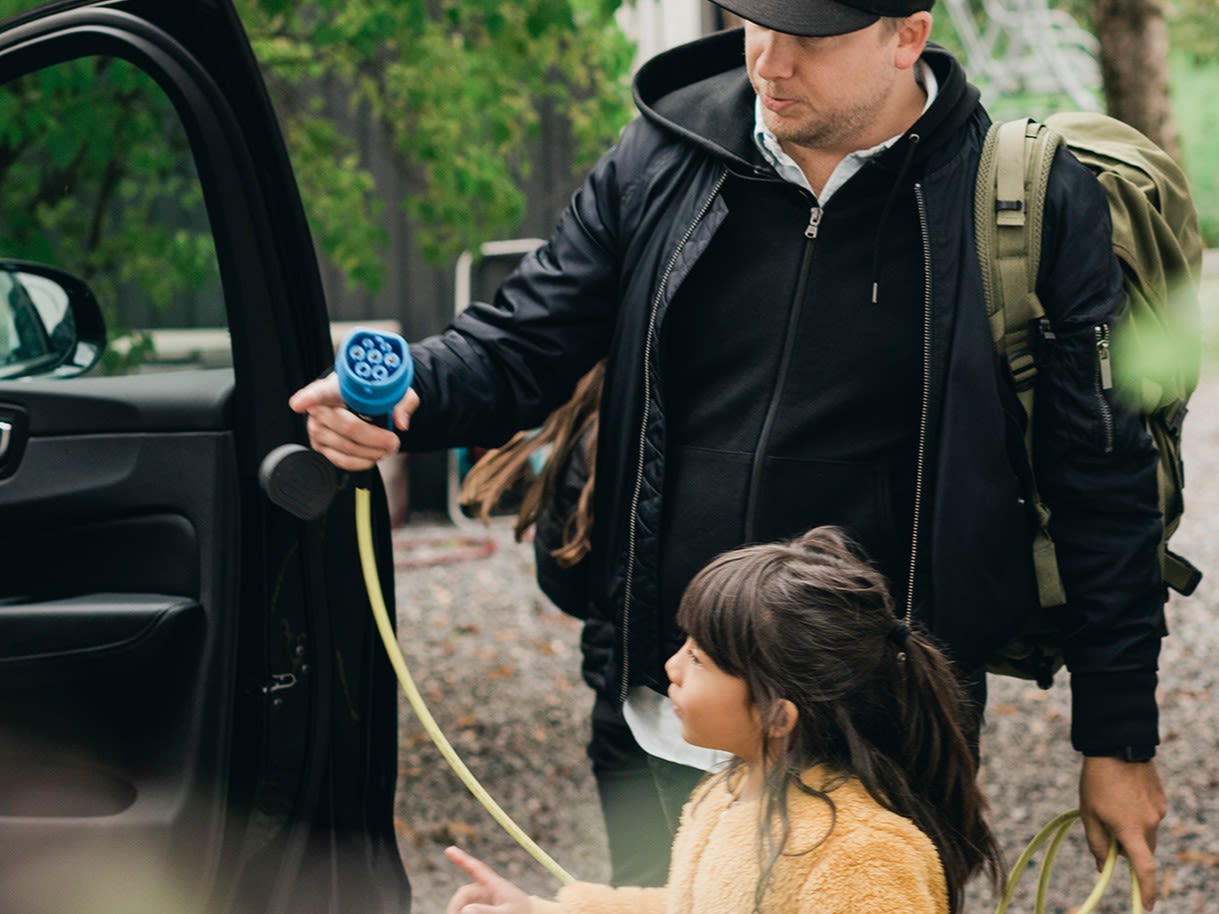 Un homme et une jeune fille sont en train de recharger une voiture électrique.