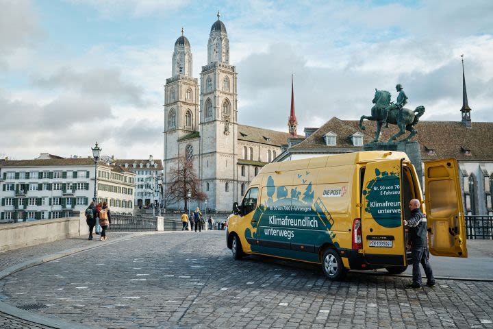Mitarbeiter der Post liefert Post mit einem Elektroauto