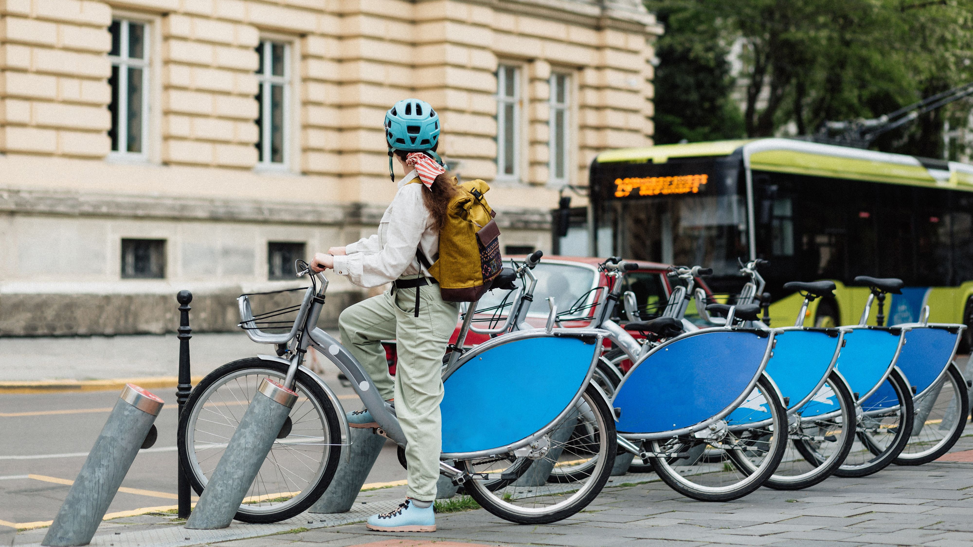 Frau auf einem Bikesharing Velo wartet, dass der Bus vorbeifährt.