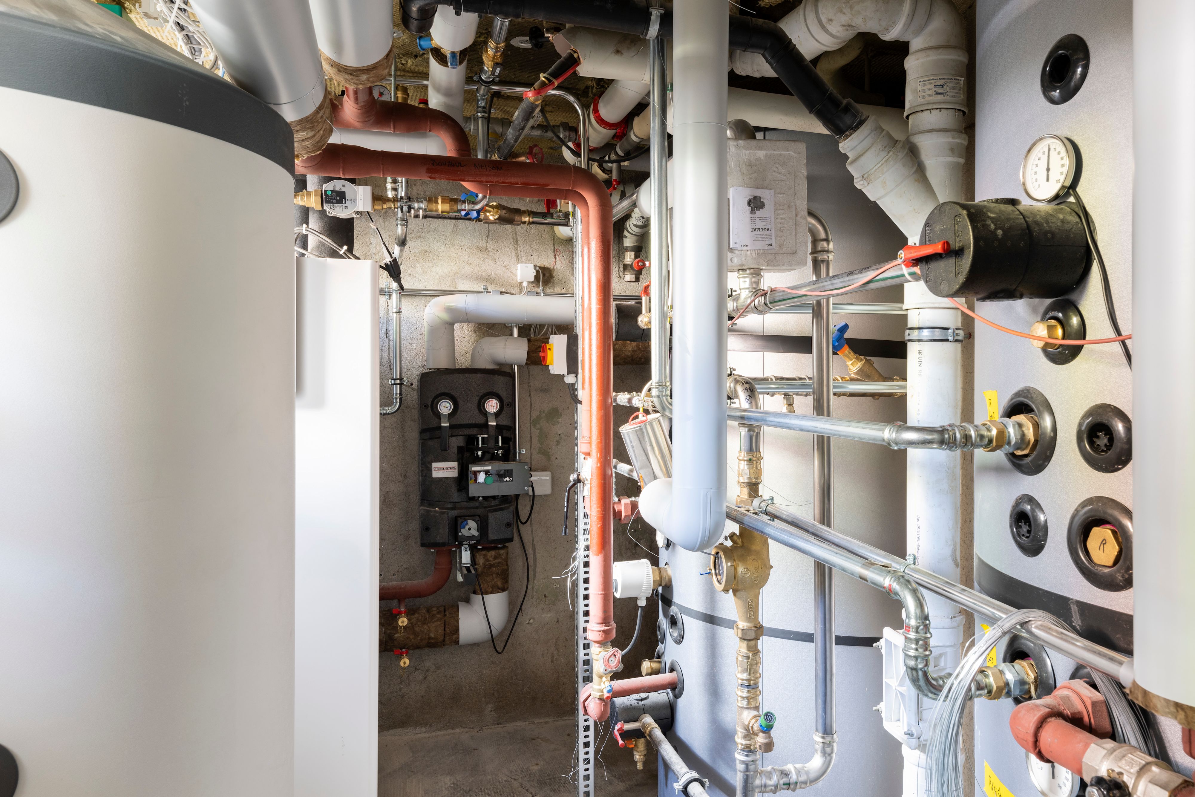 Foto der Wärmepumpe und der dazugehörigen Rohrleitungen im Keller eines Mehrfamilienhauses