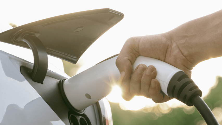 Person schliesst das Ladekabel ans Elektroauto an.