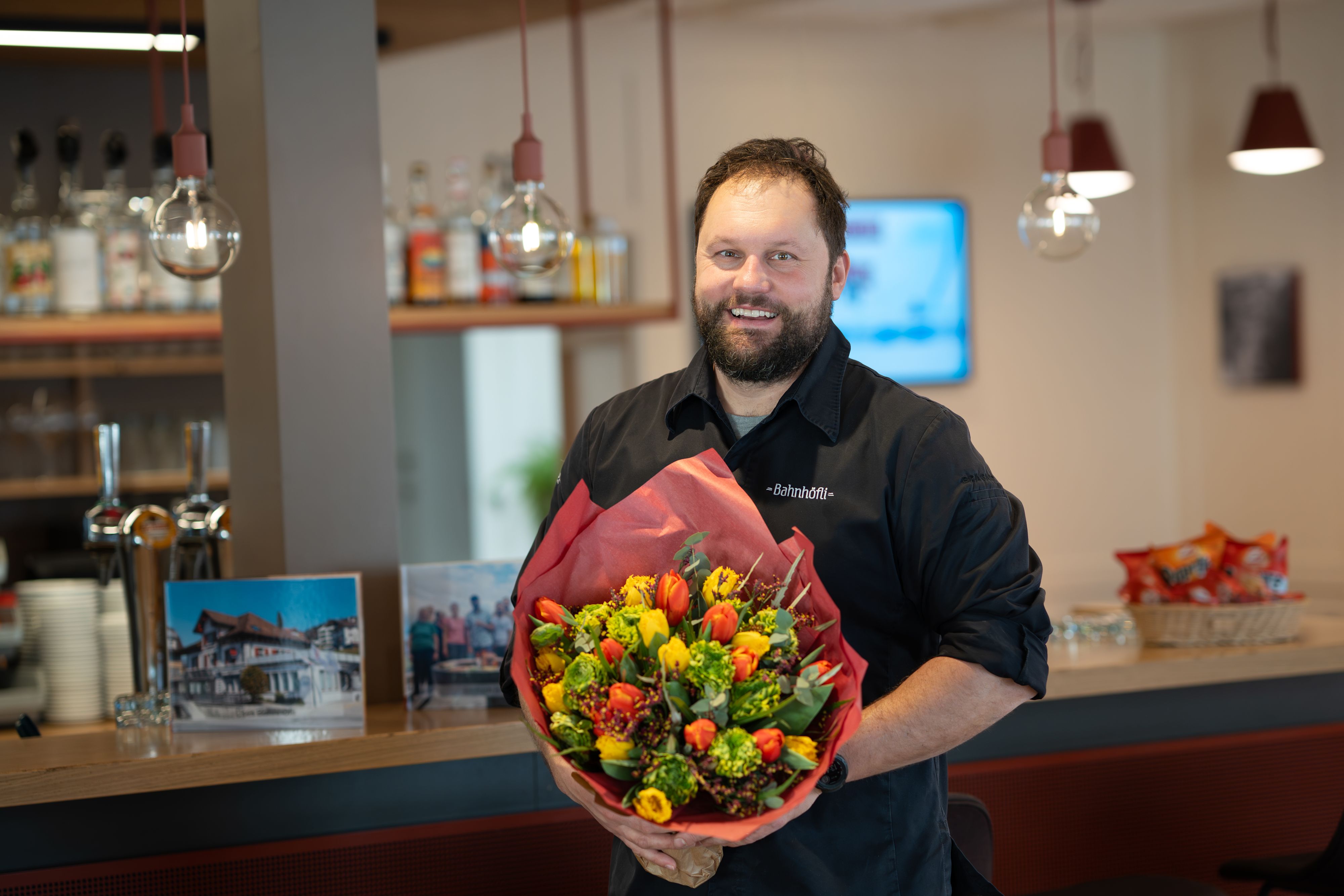 Un homme souriant avec un bouquet de fleurs
