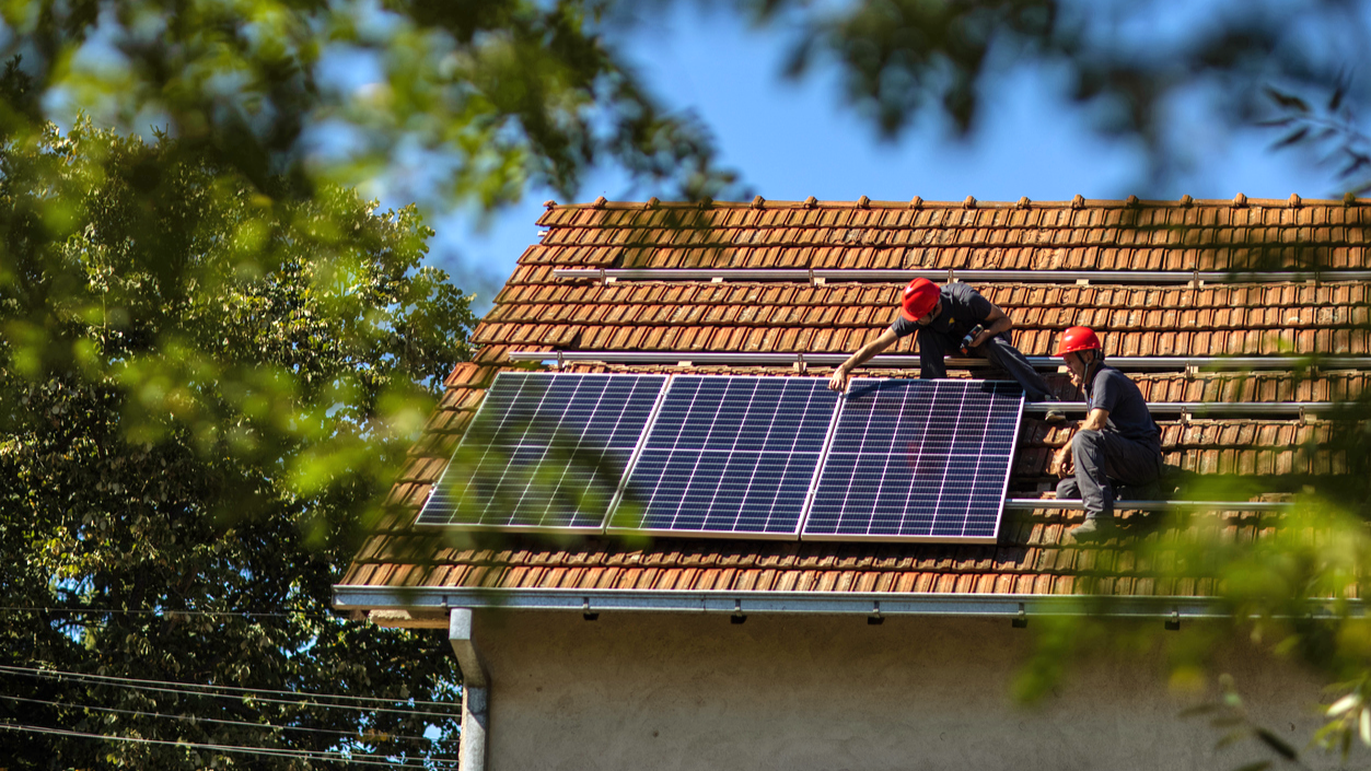 Zwei Personen installieren eine Solaranlage auf einem Dach