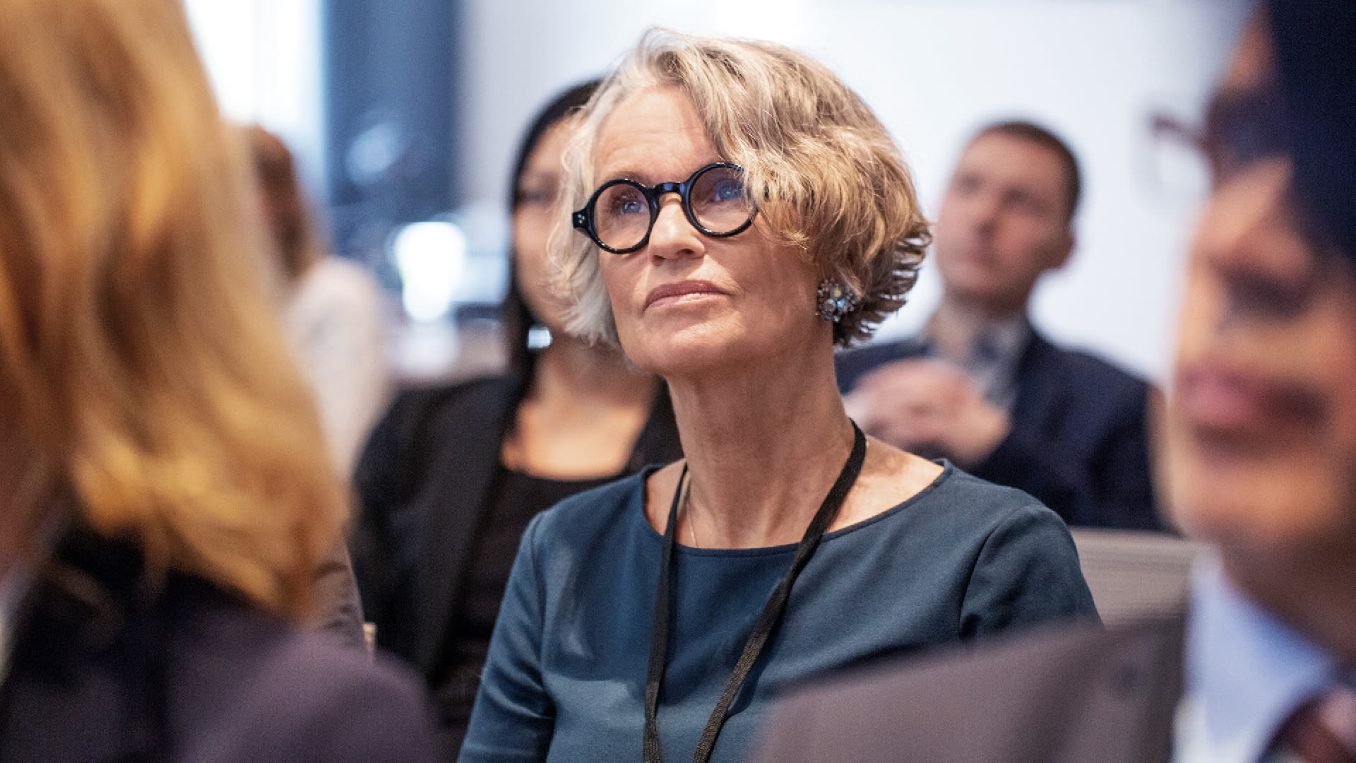 Une participante écoute attentivement une présentation lors d’un événement professionnel.