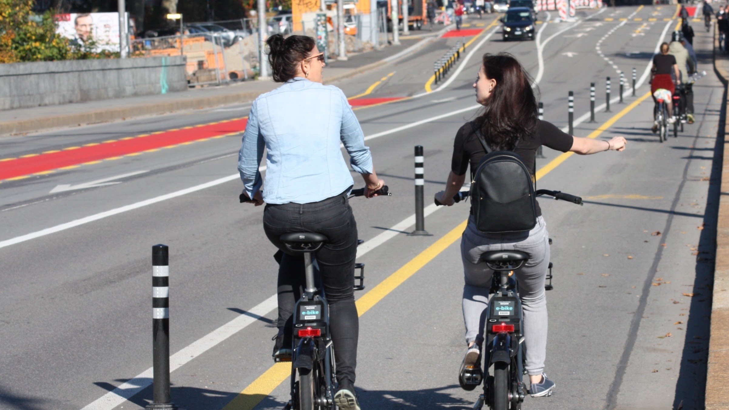 Due donne stanno percorrendo una pista ciclabile con le loro biciclette elettriche a noleggio.