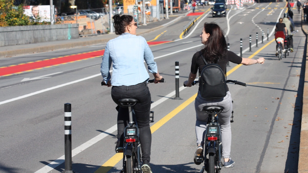 Deux femmes circulent sur une piste cyclable avec des vélos électriques loués.