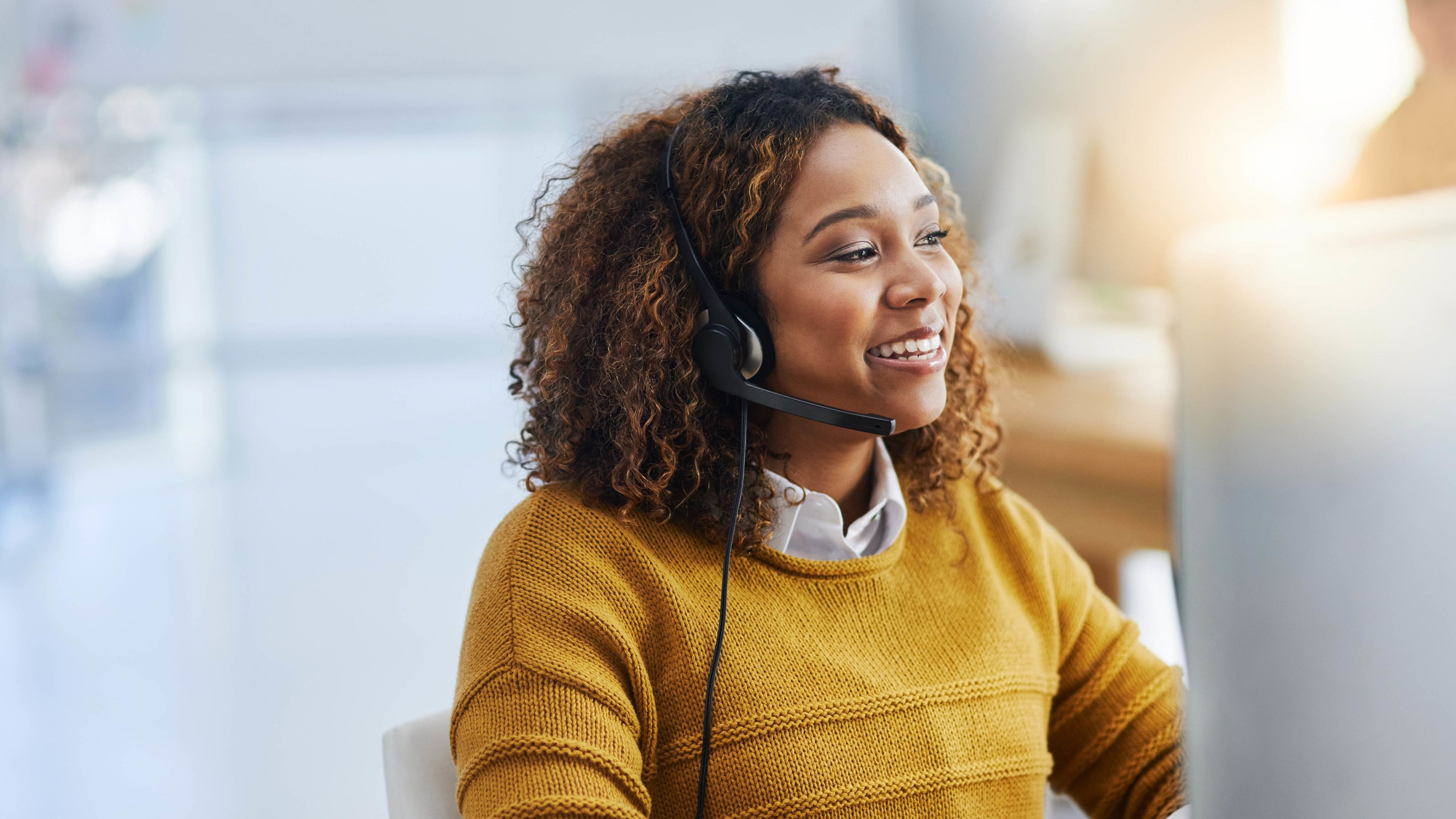 Frau am Computer telefoniert per Headset mit Kundschaft