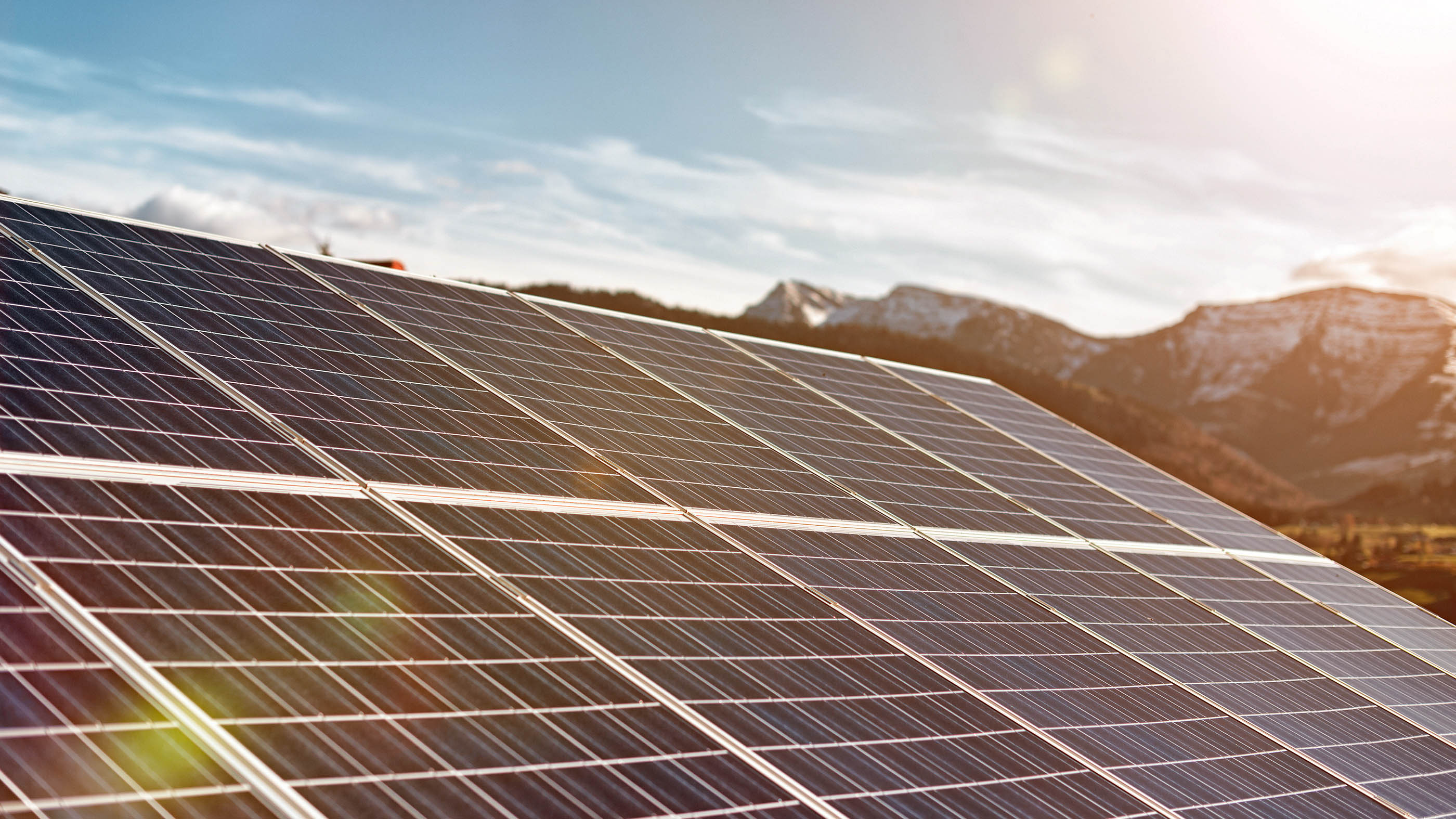 Solaranlage auf Dach vor Alpenkette.
