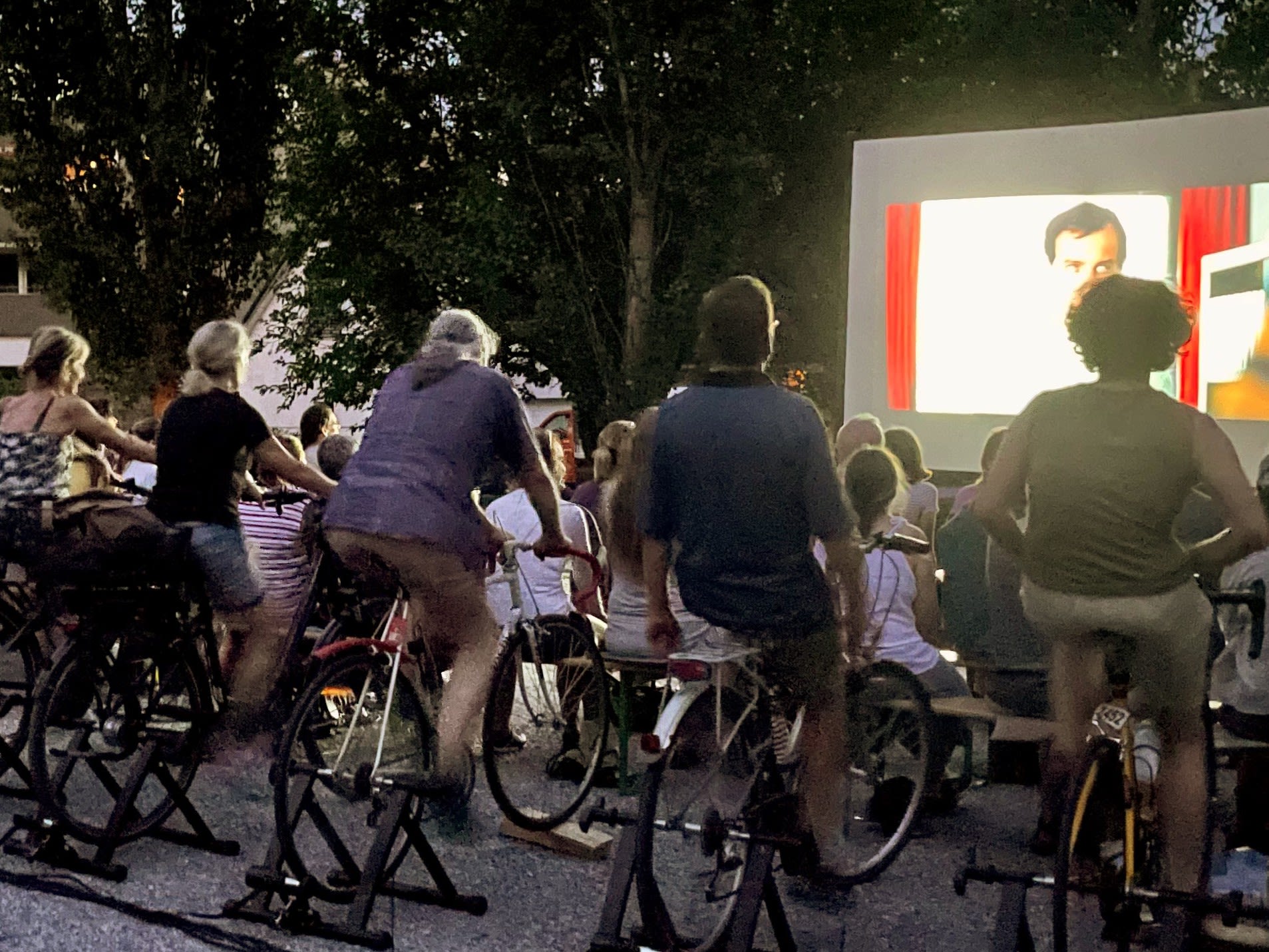 Des gens qui pédalent pour produire de l'électricité pour regarder un film dans un cinéma en plein air.