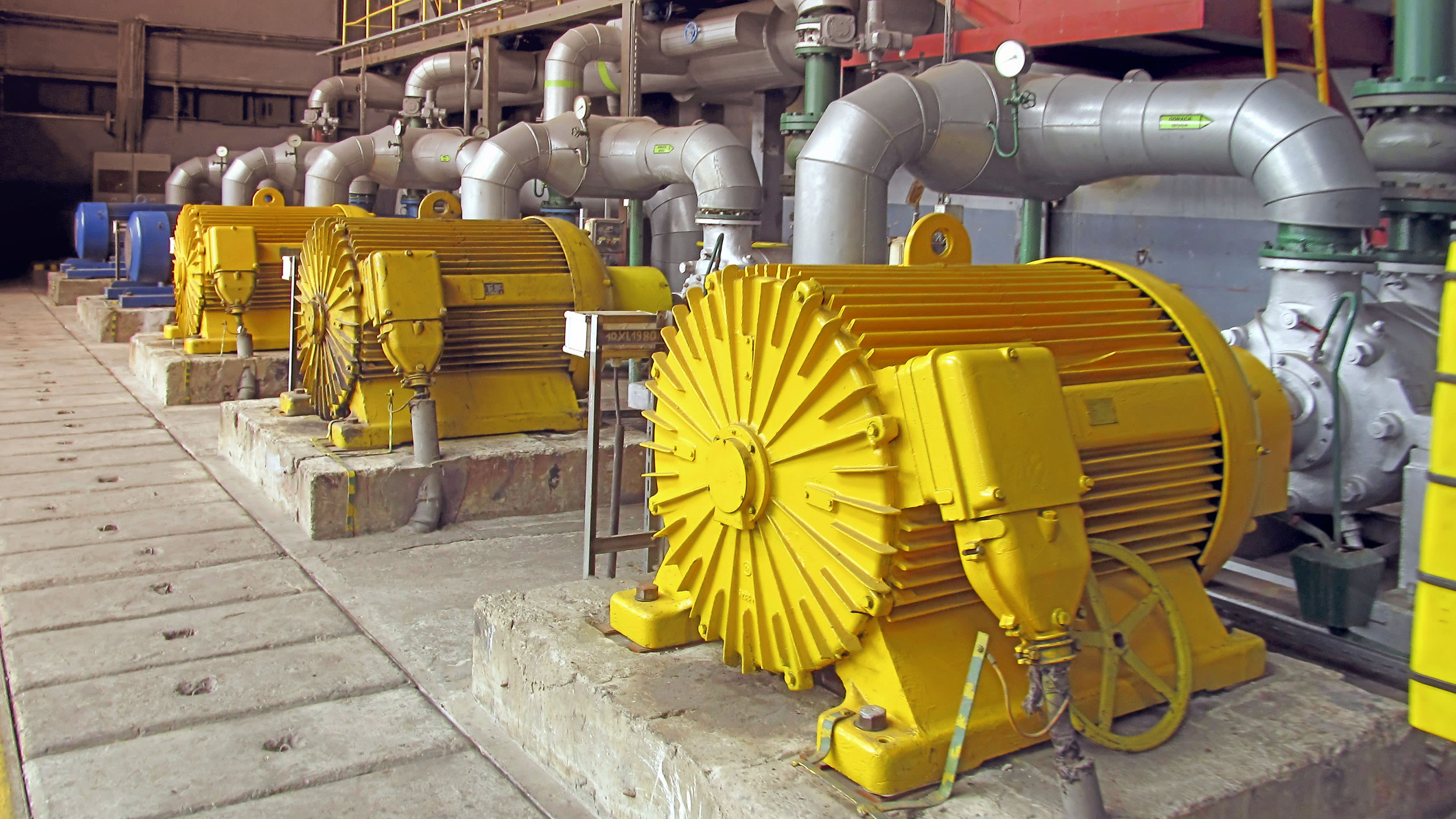 Moteurs électriques jaunes pompant de l'eau dans une installation industrielle.