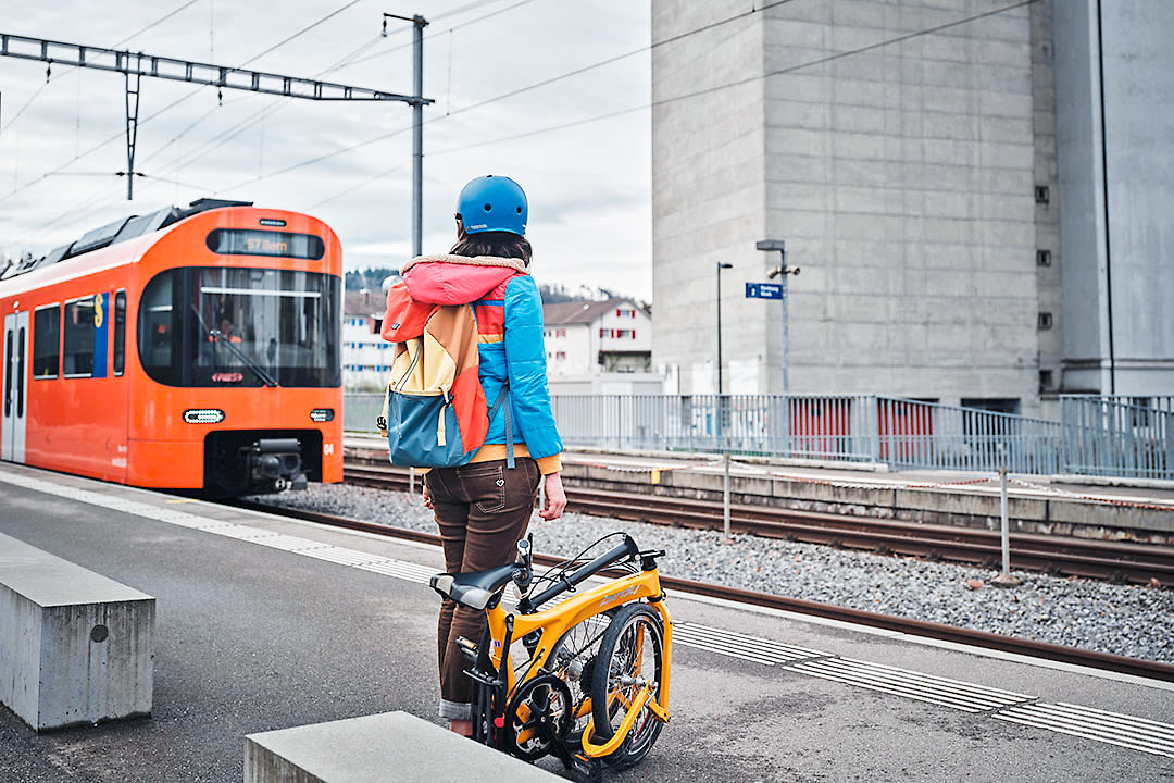 Eine Personen wartet mit ihrem Fahrrad am Bahnhof auf den Zug