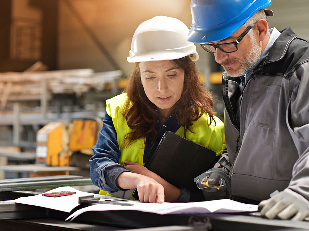 Une femme et un homme en tenue de travail discutent