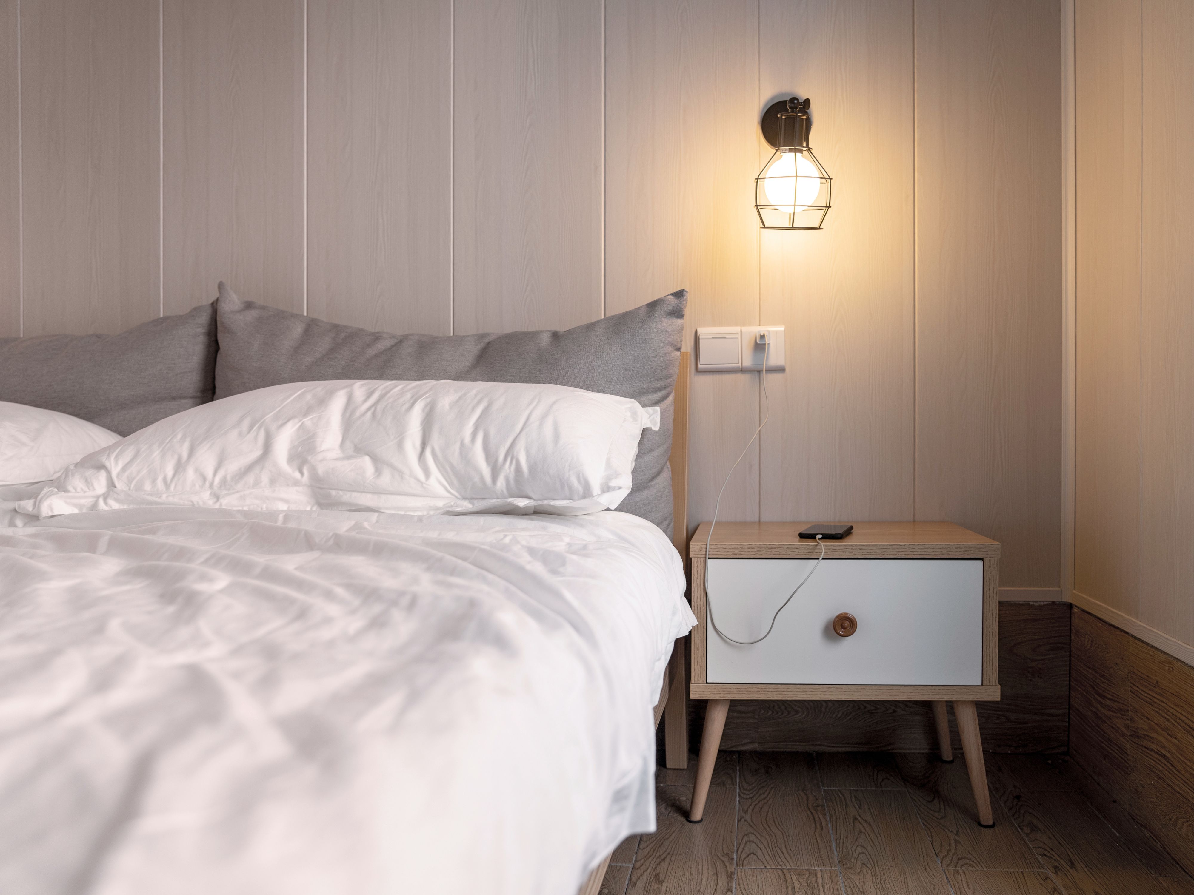 Un letto con un comodino e una lampada accesa.