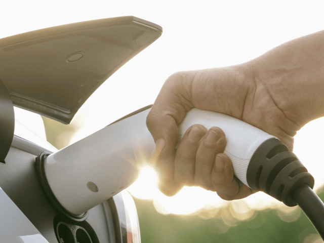 Person schliesst das Ladekabel ans Elektroauto an.