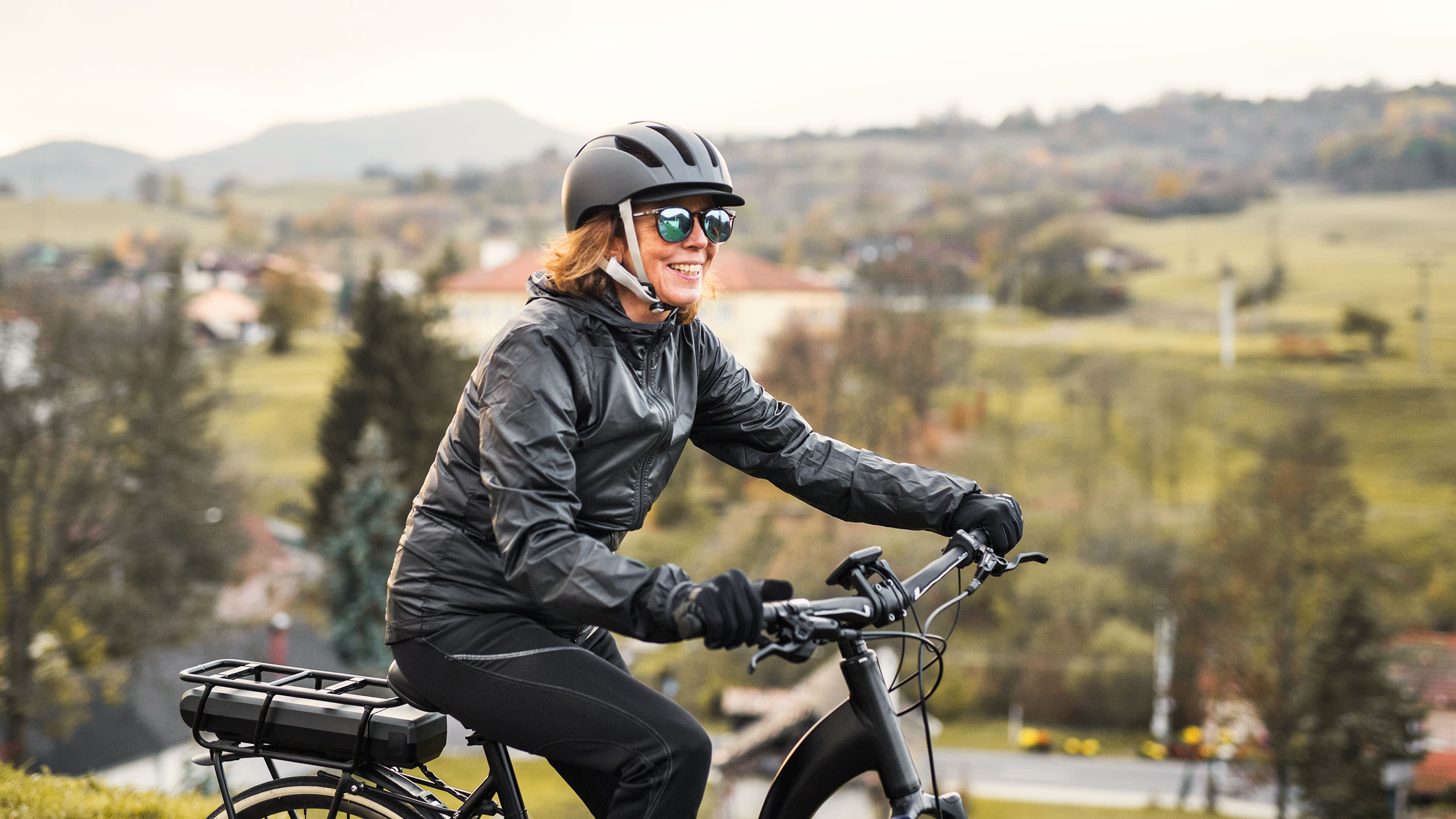 Una donna cavalca la sua bicicletta elettrica attraverso la campagna