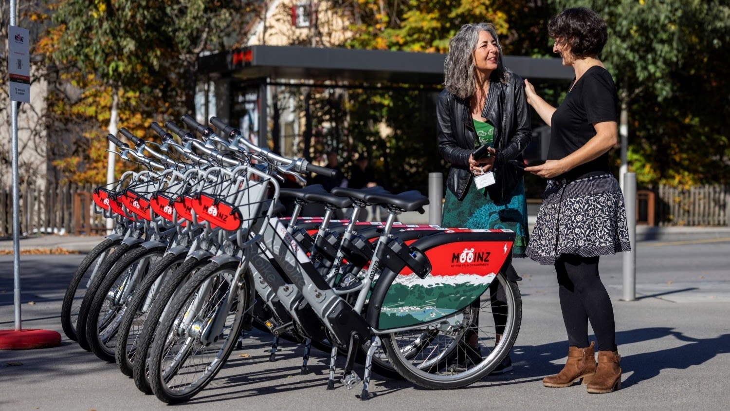 Deux femmes parlent ensemble à une station de vélos Mooinz