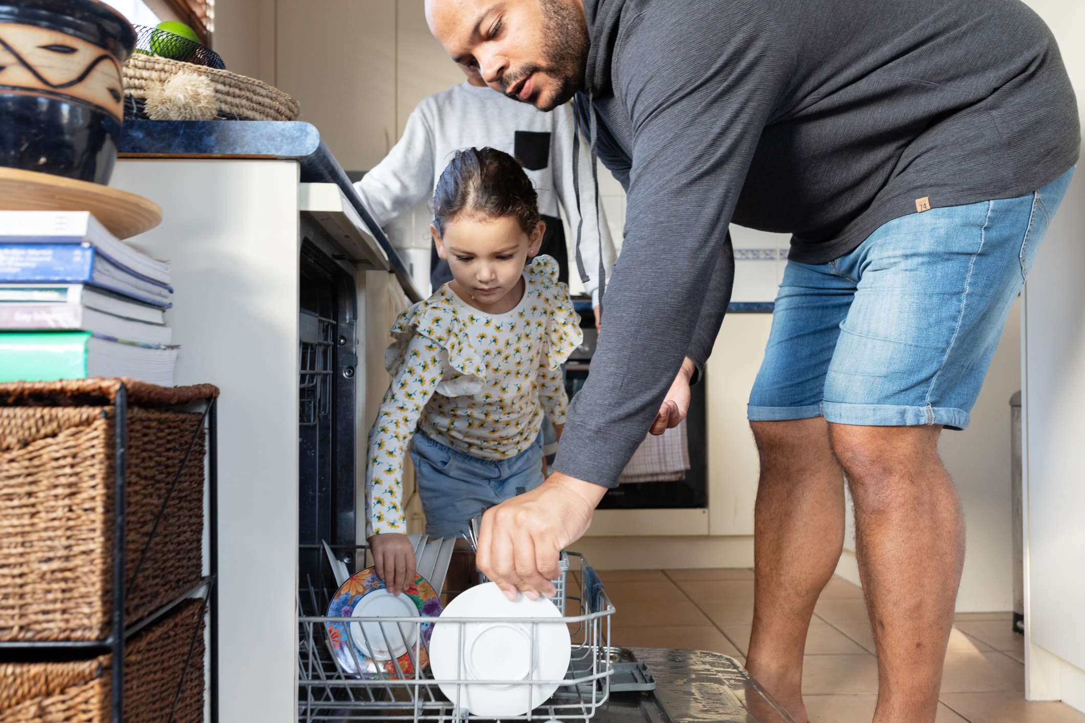 Un père et un enfant remplissent ensemble la machine à laver la vaisselle.