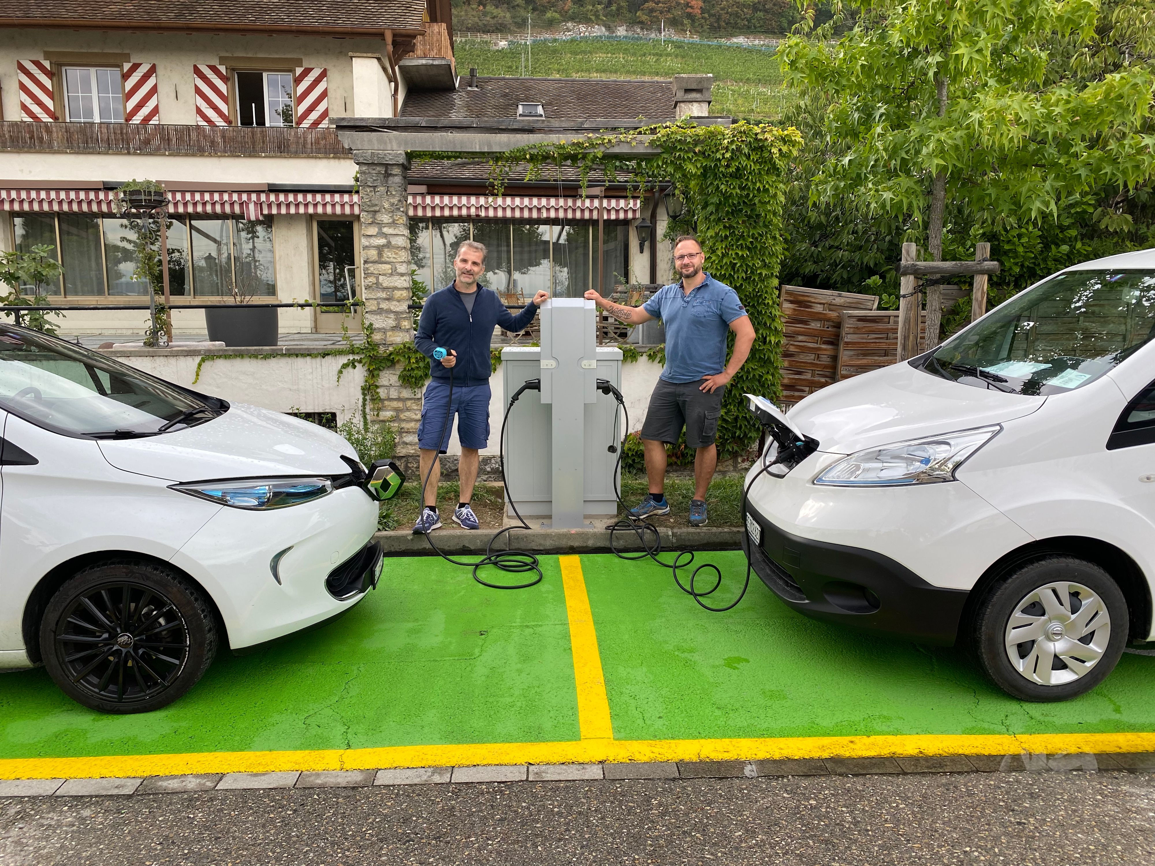 Daniel Schaller et Maik Hellmann à une borne de recharge avec deux voitures électriques