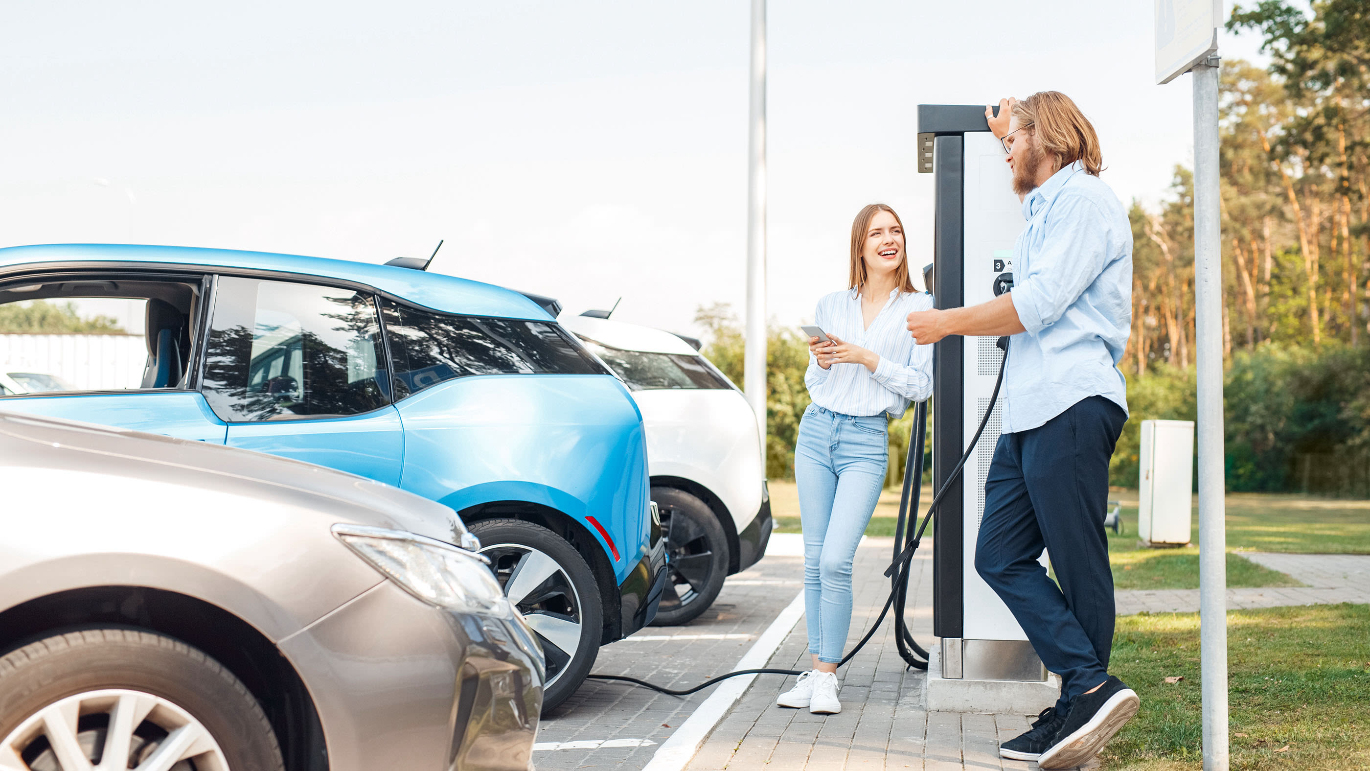 Eine Frau und ein Mann diskutieren an einer Elektrotankstelle.
