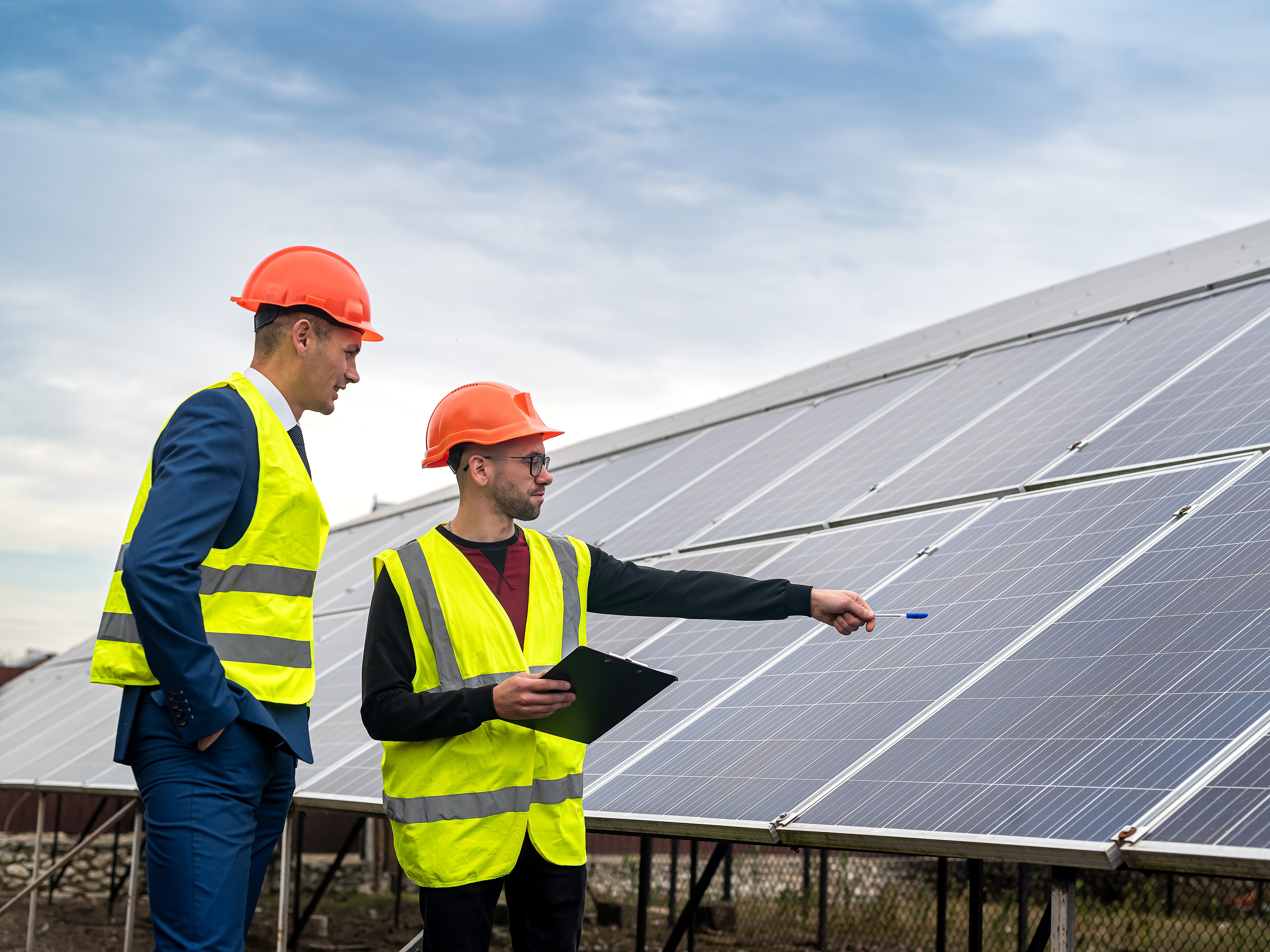 Deux hommes discutent devant une installation photovoltaïque sur un toit.