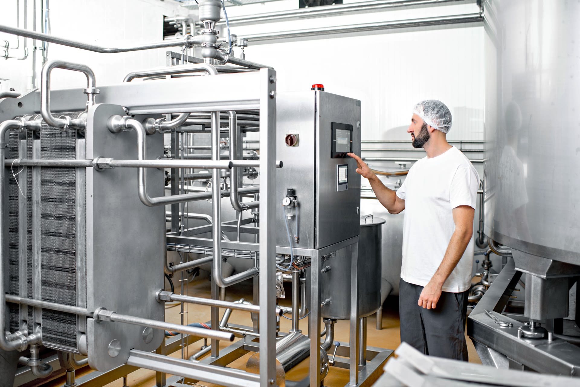 Arbeiter in Uniform bedient eine Maschine in einem Unternehmen der Lebensmittelindustrie
