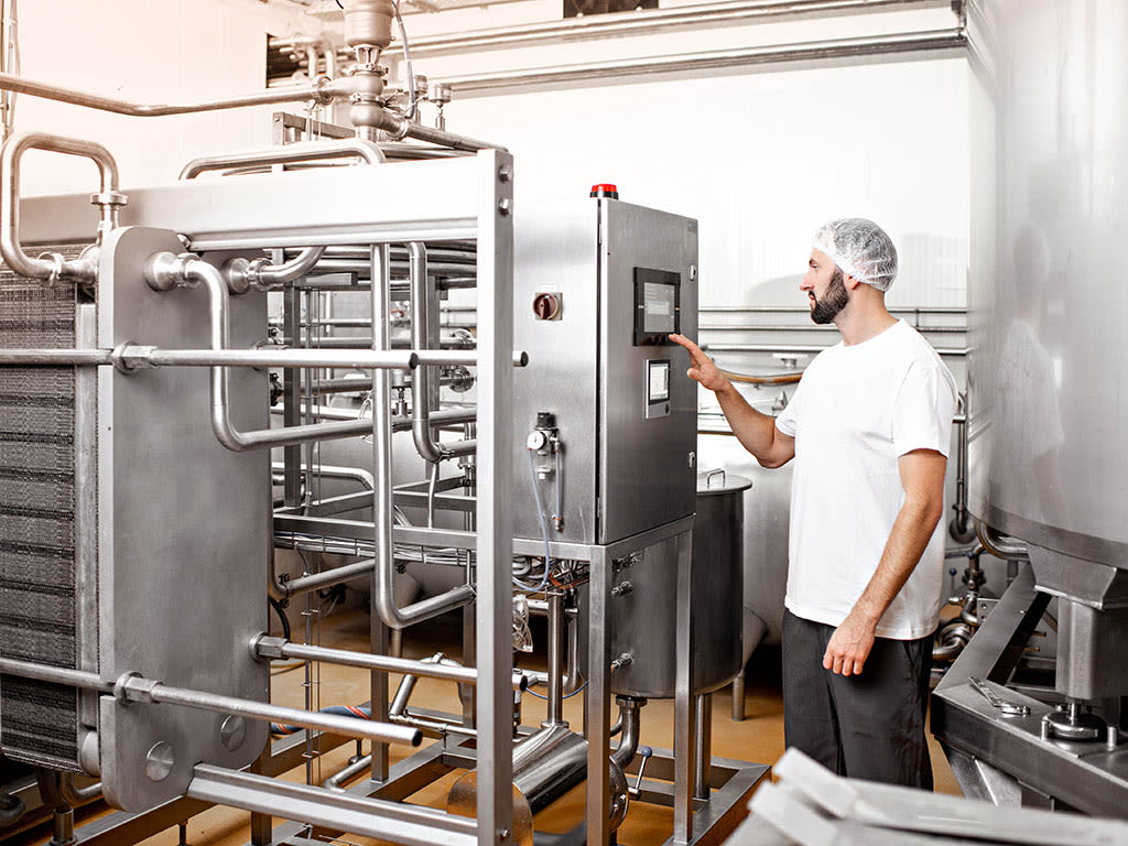 Un ouvrier en uniforme manie une machine dans une entreprise de l'industrie alimentaire