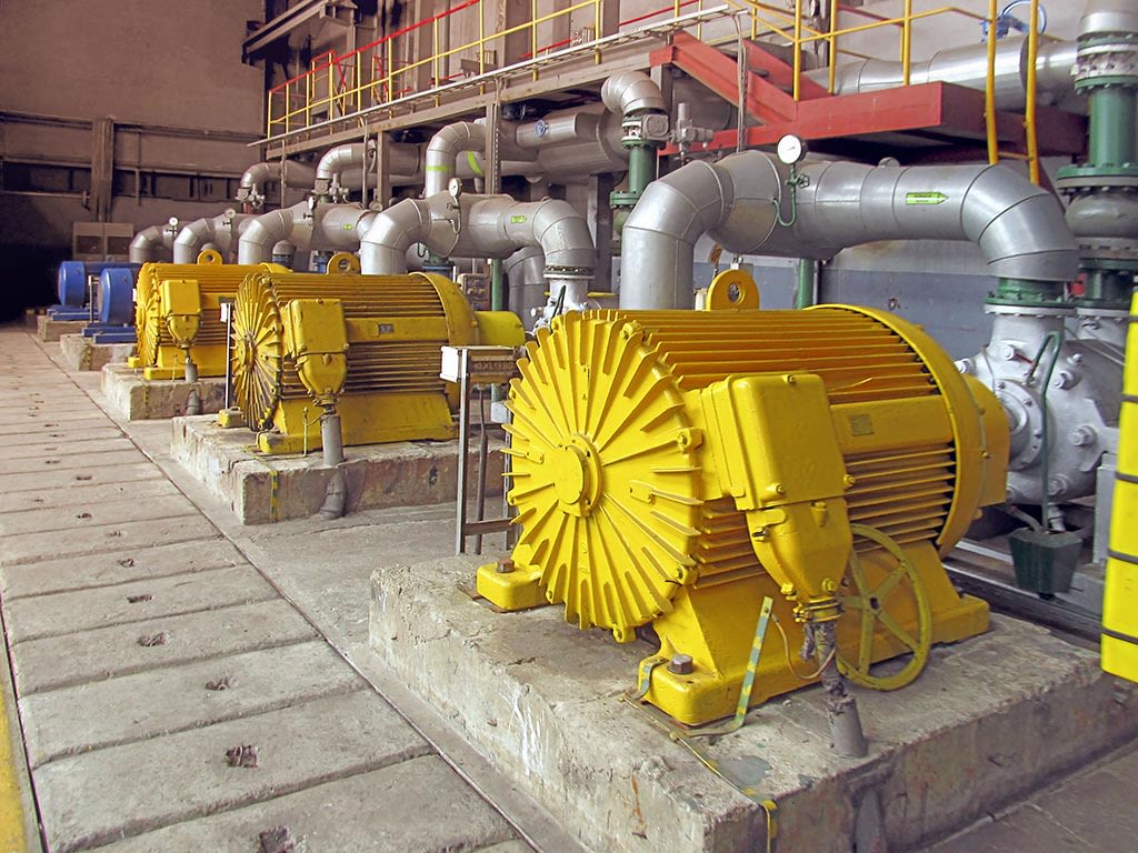 Moteurs électriques jaunes pompant de l'eau dans une installation industrielle.