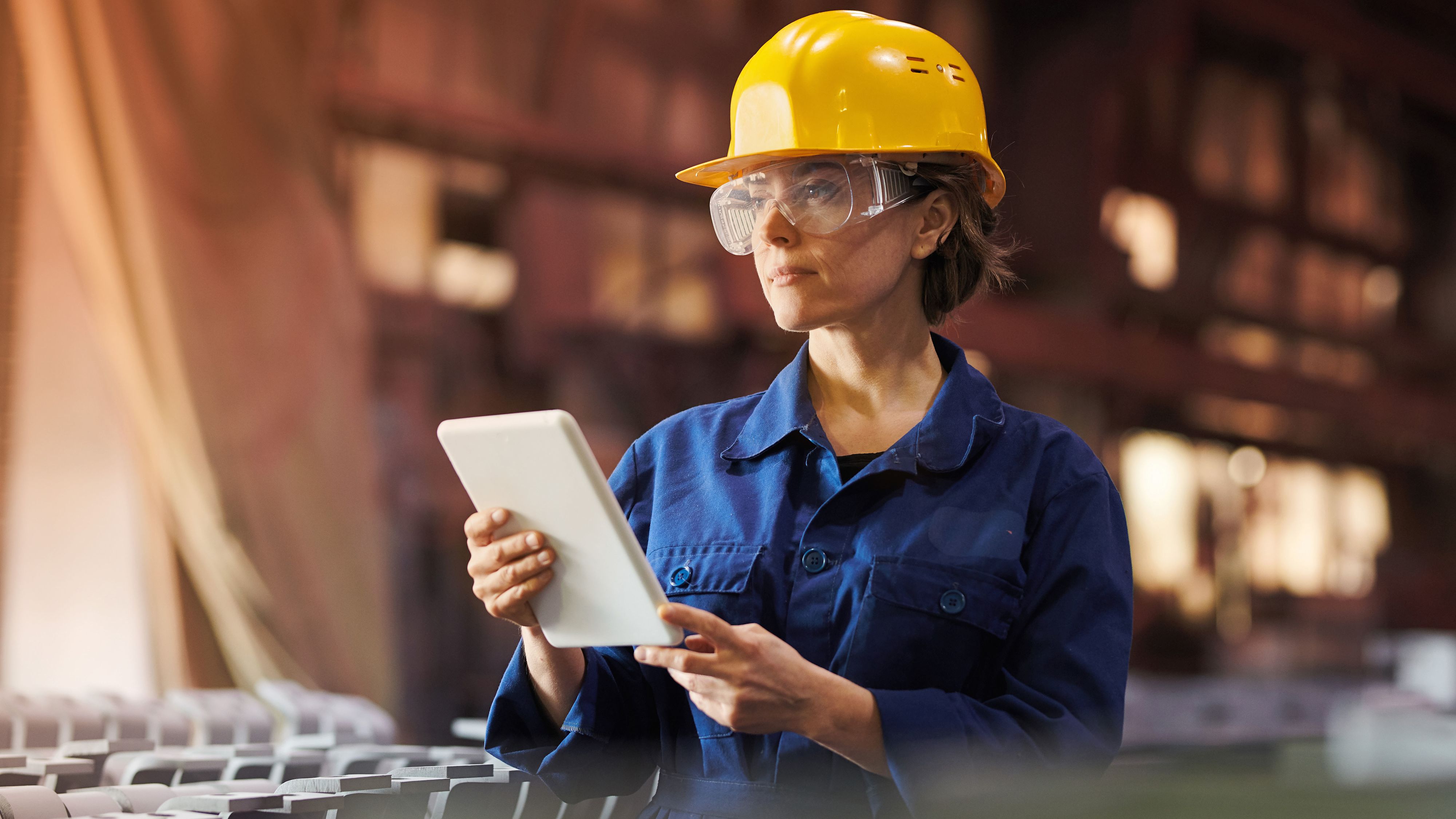 Femme professionnelle dans une entreprise industrielle avec une tablette et un casque.
