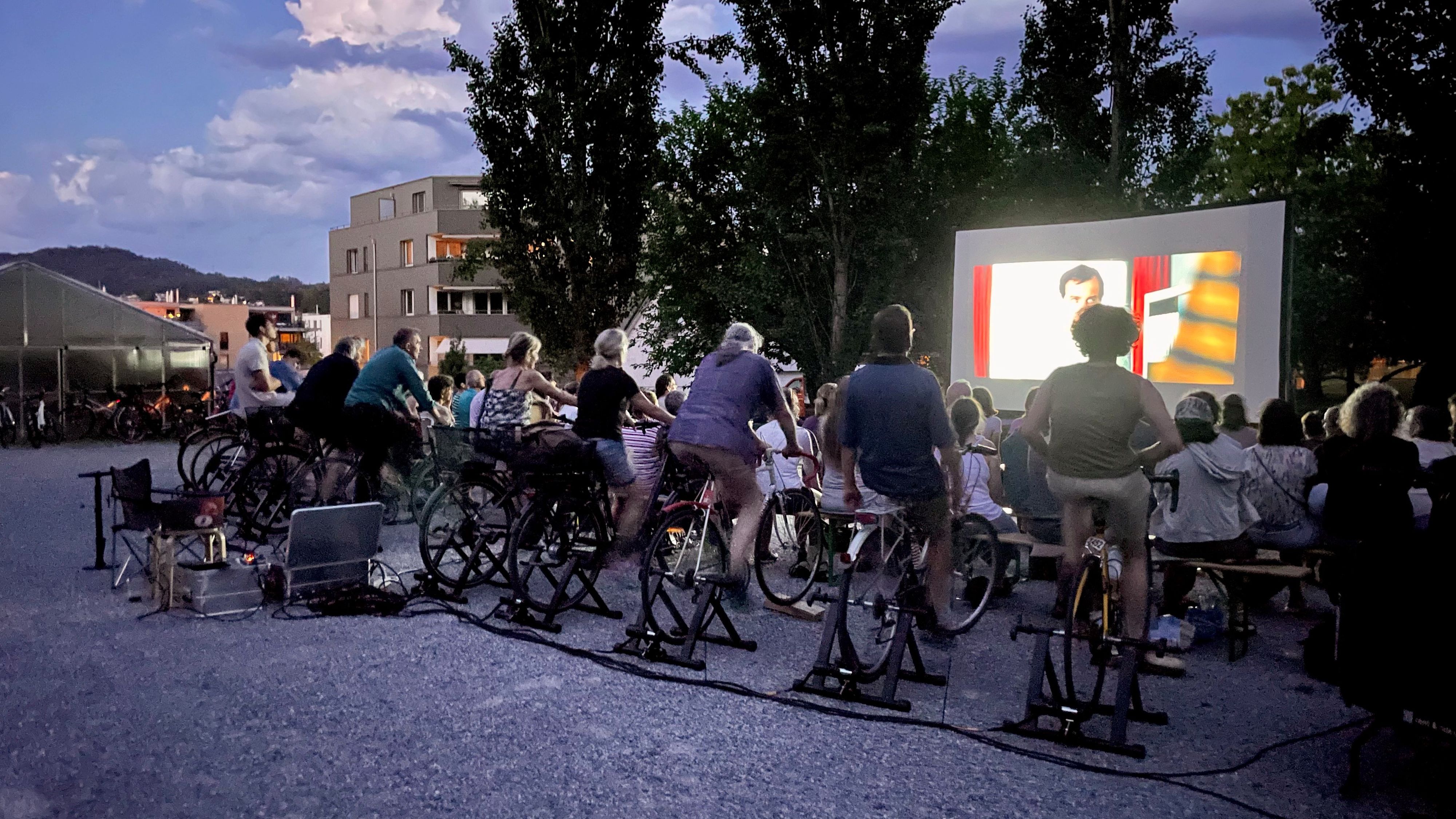 Des gens qui pédalent pour produire de l'électricité pour regarder un film dans un cinéma en plein air.