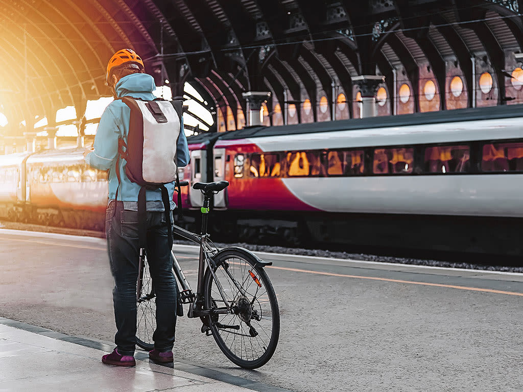 Person steht mit dem Fahrrad auf dem Bahnsteig und wartet auf den Zug.