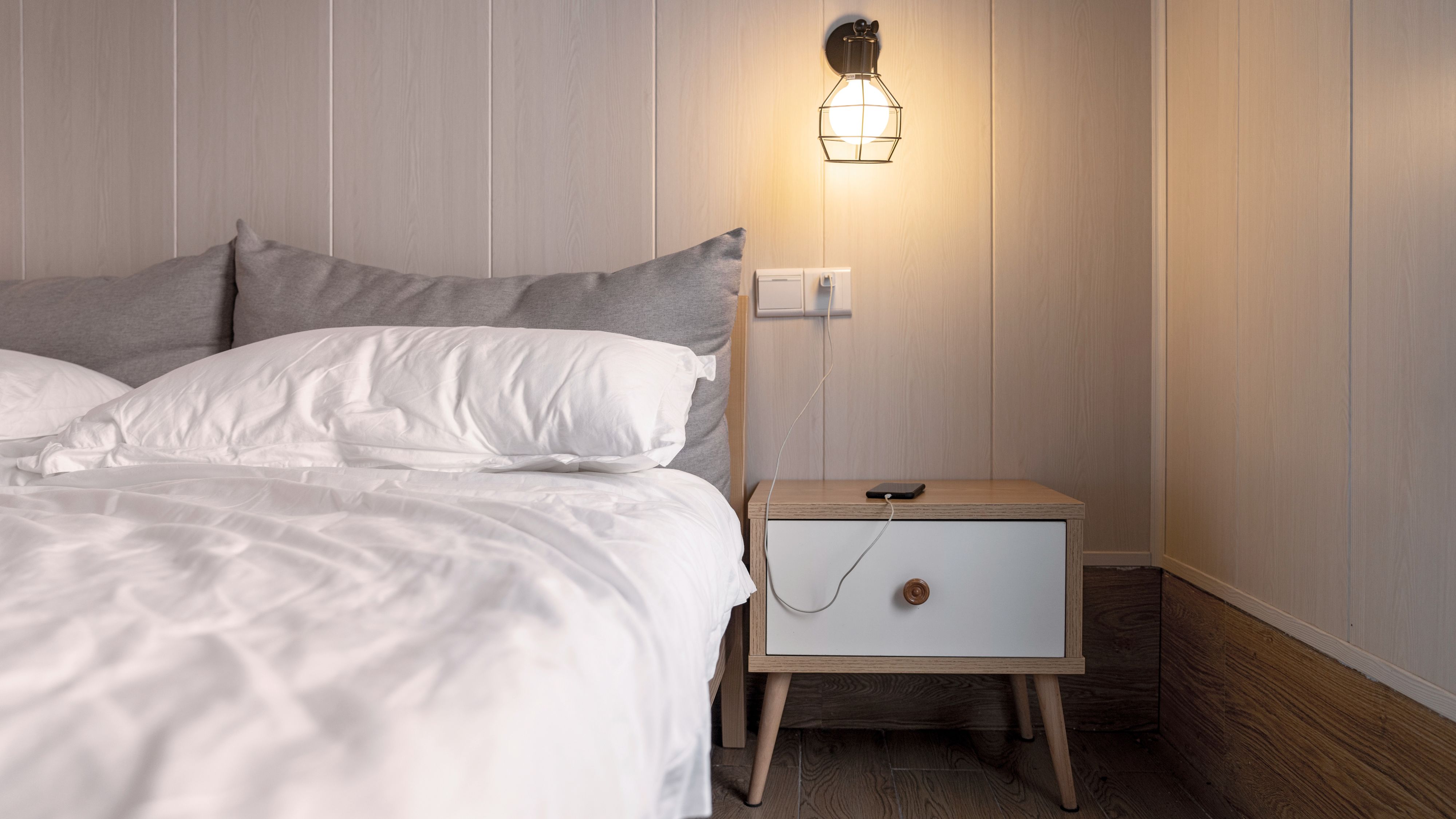 Un lit avec une table de nuit et une lampe allumée.