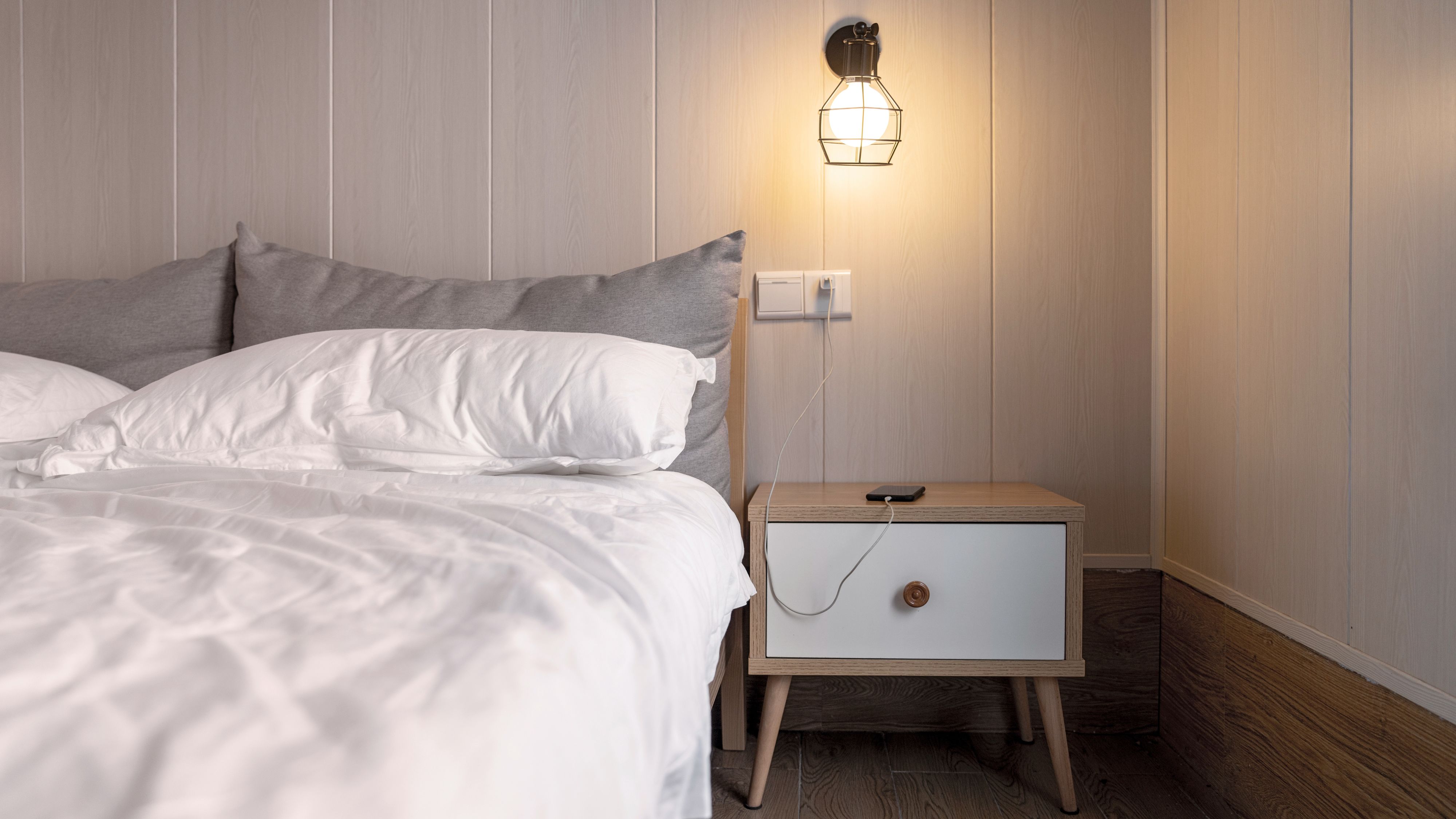 Bett mit Nachtisch und brennender Lampe.