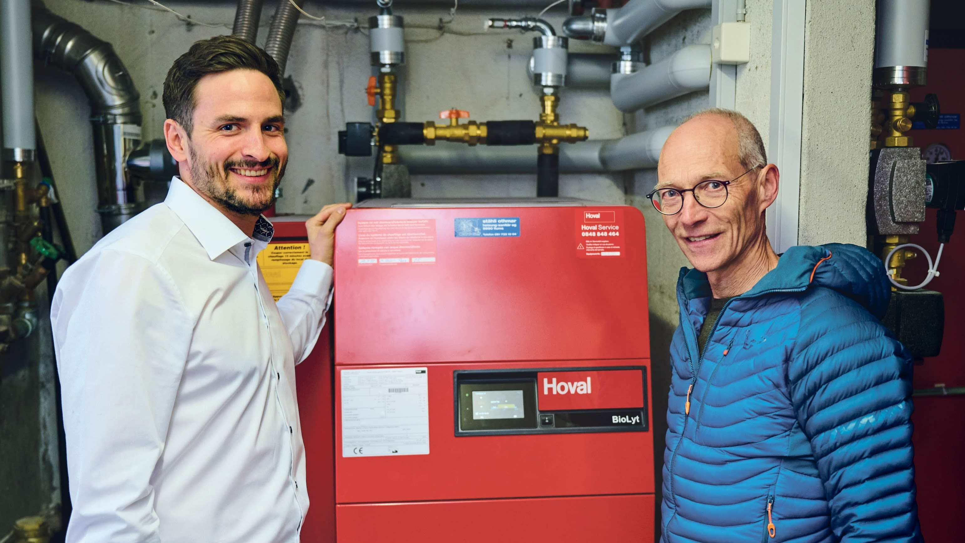 Justus Gallati et Fabian Burkhalter devant le chauffage à pellets combiné à l'énergie solaire thermique qui a remplacé le chauffage au mazout.