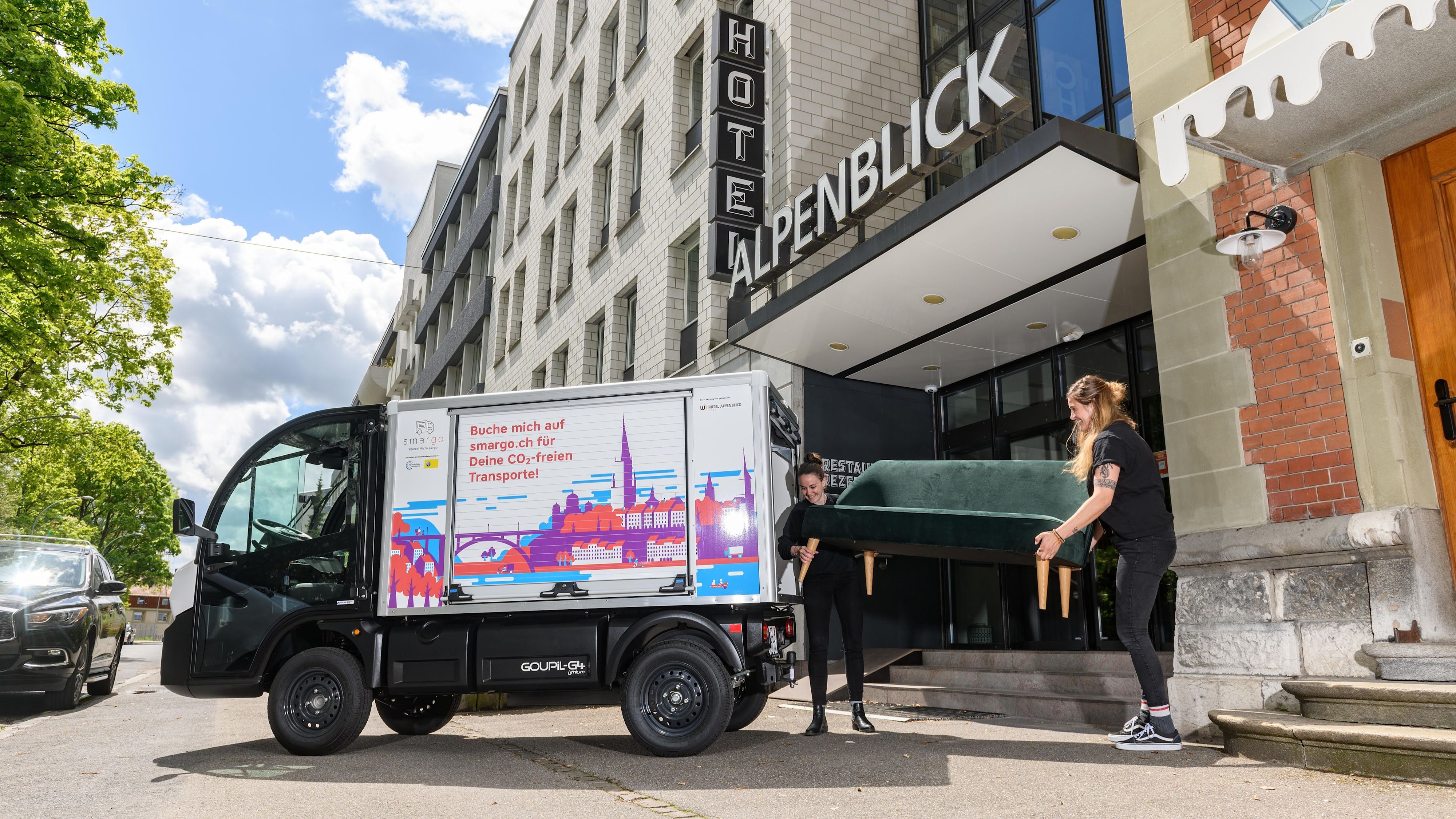 Zwei Frauen laden ein Sofa in einen E-Kleintransporter.
