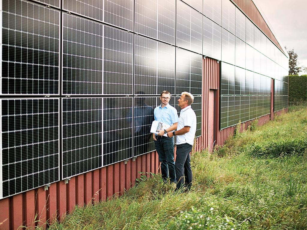 Deux hommes se délibèrent devant un bâtiment avec une façade solaire