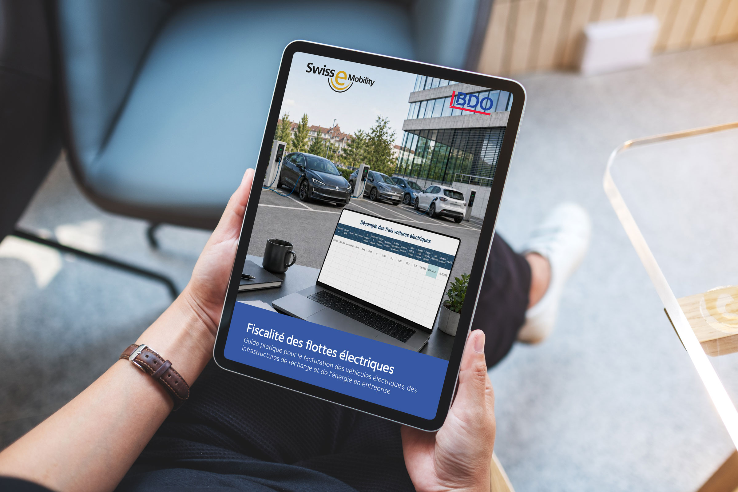 Une personne tient une tablette dans la main qui montre le guide «Fiscalité des flottes électriques».