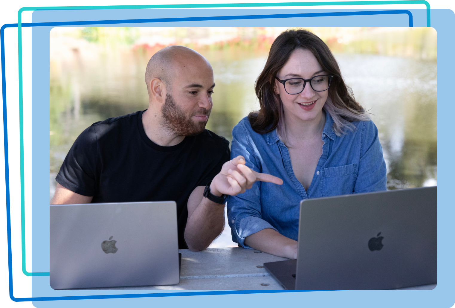 two people sitting next to each other working on laptops