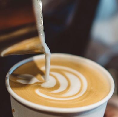 Milk being poured into a latte coffee to create a pattern