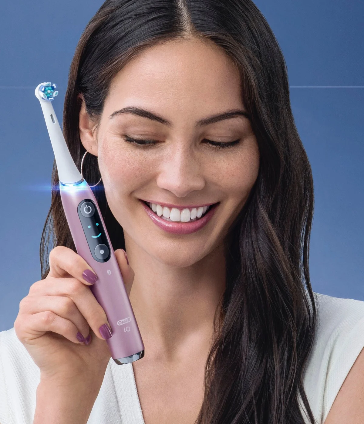 Leende kvinna som håller i Orchid Purple Oral-B iO eltandborste 