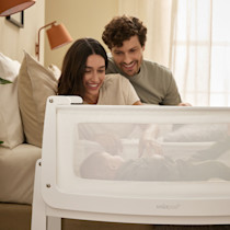 Parents interacting with baby inside SnuzPod5 bassinet