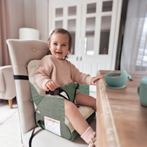 Child sitting in booster seat at a dining table